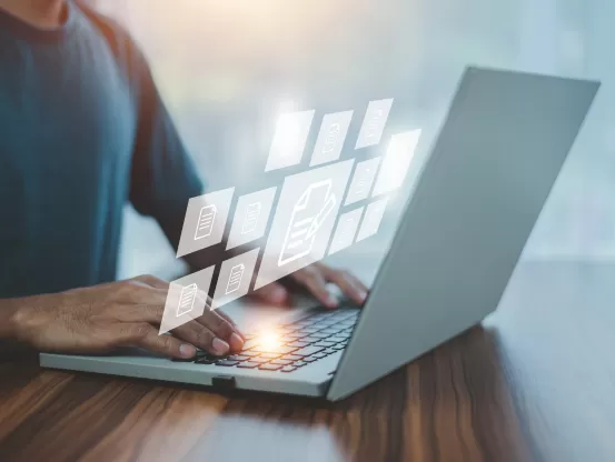 Laptop with pale graphics floating over it and a person typing 